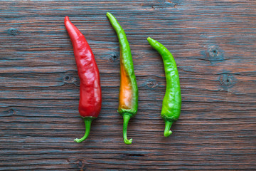 Three hot peppers on a wooden table. View from above.