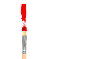 Brush with red paint and red brush stroke on a white background, top view, copy space.