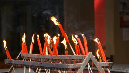 Video 4k of flame from burning red chinese candle in the temple