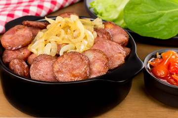 Sliced and fried Calabrese sausage in a pub table in wood background close