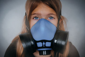 Young girl wearing gasmask, respirator portrait. Effects of worldwide air pollution, industrial...