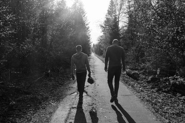 Two friends are walking along the alley, sad mood, atmosphere of quarrel or resentment; black and white photo