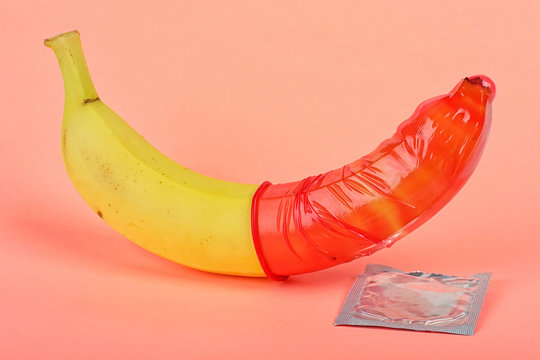 Red condom and banana on pink background. Safe sex concept. World AIDS Day concept.