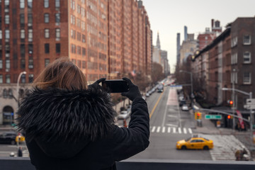 young woman taking a picture with a smartphone in the streets of new york
