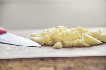 Chopped potato on a wooden surface with a knife on a side