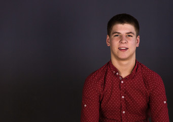 Portrait of a guy of European appearance in a red shirt.  Shooting in the studio, plain background.