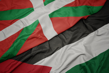 waving colorful flag of palestine and national flag of basque country.