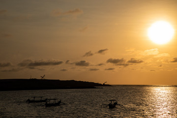 Sunset view of the beach with boats silhouettes in Bali