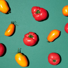 Yellow and red tomatoes pattern on green background. Flat lay, top view. Summer minimal concept. Vegan and vegetarian diet.