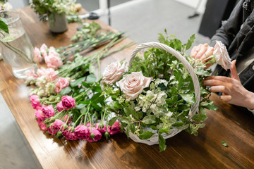 Woman florist create flower arrangement in a wicker basket. Beautiful bouquet of mixed flowers. Floral shop concept . Handsome fresh bouquet. Flowers delivery