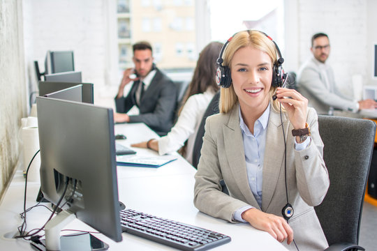 Portrait of smiling female customer service representative with colleagues working in office