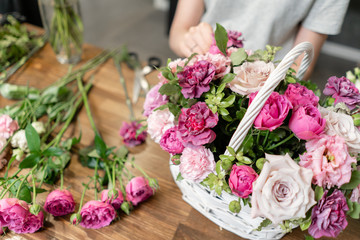Woman florist create flower arrangement in a wicker basket. Beautiful bouquet of mixed flowers. Floral shop concept . Handsome fresh bouquet. Flowers delivery