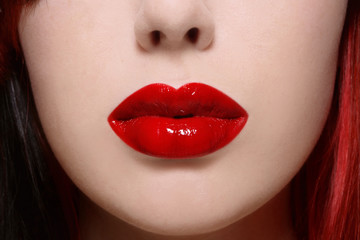 Close-up shot of beautiful woman lips with glossy red lipstick