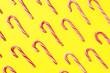 Pattern of Christmas candy cane on yellow background. Top view. Flat lay. Creative minimal concept. Greeting card on Christmas and New Year. Art composition.