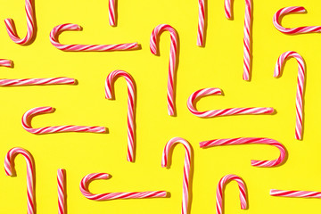 Pattern of Christmas candy cane on yellow background. Top view. Flat lay. Creative minimal concept. Greeting card on Christmas and New Year. Art composition.