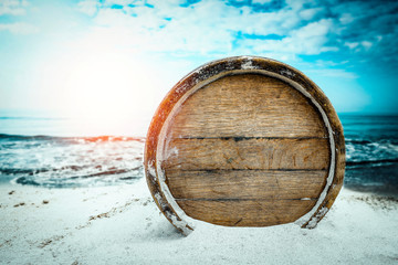 Old wooden barrel on the sandy beach with dark blue ocean view.