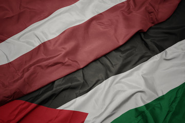 waving colorful flag of palestine and national flag of latvia.