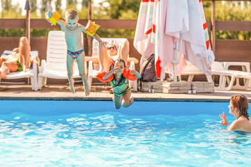Group Of Children Jumping Into Outdoor Swimming Pool