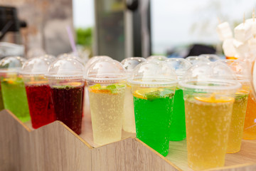 A counter with multi-colored fruit cocktails in plastic cups. Food and cooking equipment at a street food festival
