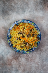 Obraz na płótnie Canvas Traditional Uzbek pilaf with mushrooms. Vegetarian pilaf on a platter. Clean food concept.