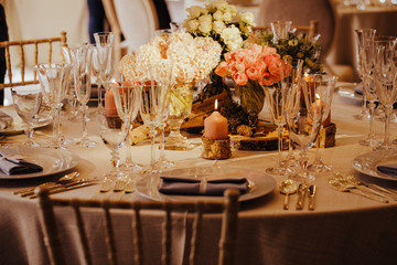 Table set for an event party or wedding reception. Beautiful flowers on the table. Warm colours.