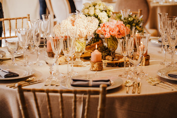 Table set for an event party or wedding reception. Beautiful flowers on the table. Warm colours.