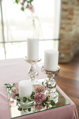 The wedding table setting for the newlyweds is decorated with fresh flowers of carnation, rose, anthurium and eucalyptus leaves. Silver candlesticks, white candles. Wedding floristry. Closeup details