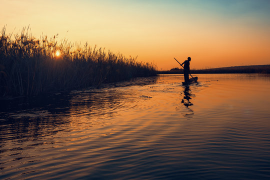 Man poling a dugout canoe at sunset in Cuando river