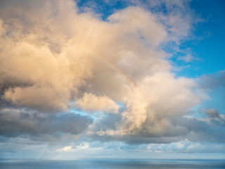 clouds in the blue sky with little rainbow on Faroe island. Big size.