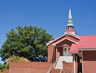 Red Brick Church with Green Steeple, Metal Roof, White Door and Tree