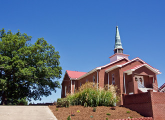 Red Brick Church with Green Steeple, Metal Roof,  White Door and Tree