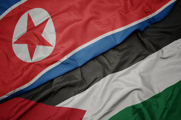 waving colorful flag of palestine and national flag of north korea.