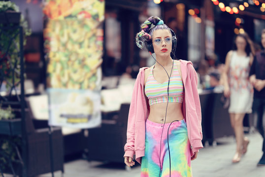 Modern fashion vanguard woman on the streets with trendy eyeglasses and piercings, listening music on headphones - Unique Avant-garde confident young woman - Urban fashion