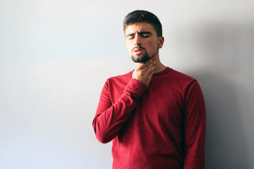 Medicine and Health Concept: Young boy dressed in red with a sore throat on a white background.