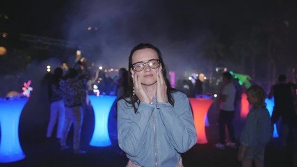 Woman in glasses is dancing night at the disco party. Dancing people disco lights and smoke.