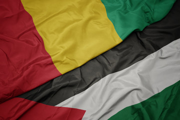 waving colorful flag of palestine and national flag of guinea.