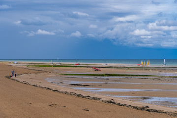 Luc-Sur-Mer, France - 08 12 2019:  View of the beach from with groups of people and sailing boats