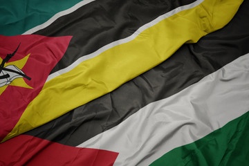 waving colorful flag of palestine and national flag of mozambique.