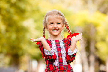 little girl blonde first grader red plaid dress smiling in the street