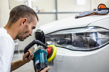 Car detailing - Hands with orbital polisher in auto repair shop. Selective focus.