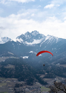 Two people flying with a Tandem and enjoying the freedom, high up in the sky with a few clouds and mountains covered in snow in the background