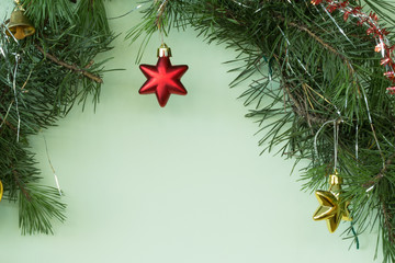 .Christmas background. Decoration of natural pine branches on a green background with a Xmas red star. Copy space. Macro photo.