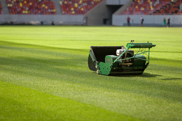 Industrial lawn mower machine on a soccer stadium with freshly installed and trimmed new turf