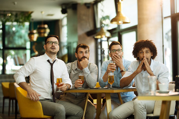 Friends are happy while watching game at te ub and drinking beer.