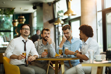 Friends are happy while watching game at te ub and drinking beer.