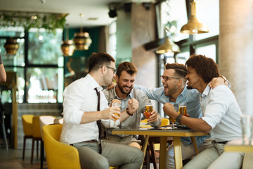 Friends are happy while watching game at te ub and drinking beer.