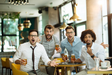 Friends are happy while watching game at te ub and drinking beer.