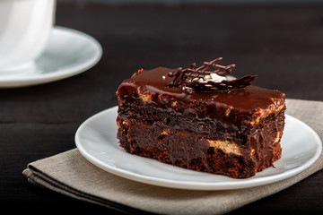 Dish with a slice of chocolate cake stands on a wooden table