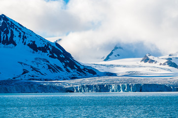 The end of a glacier in the Arctic Circle where it falls into the Arctic Ocean in Hornsund,...