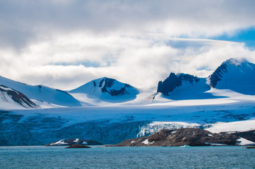 The end of a glacier in the Arctic Circle where it falls into the Arctic Ocean in Hornsund,...
